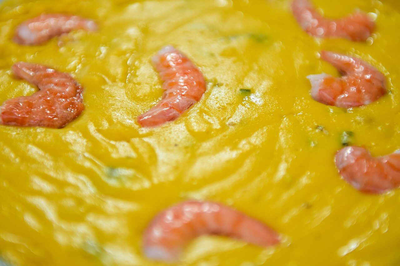 Bobó de camarão cremoso e amarelo com camarões inteiros por cima