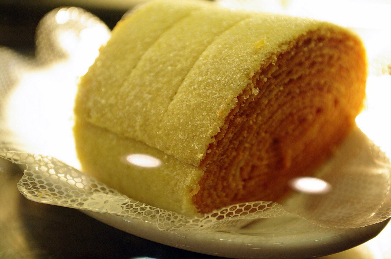 Fatia de bolo de rolo pernambucano mostrando as camadas finas de massa e goiabada enroladas em espiral